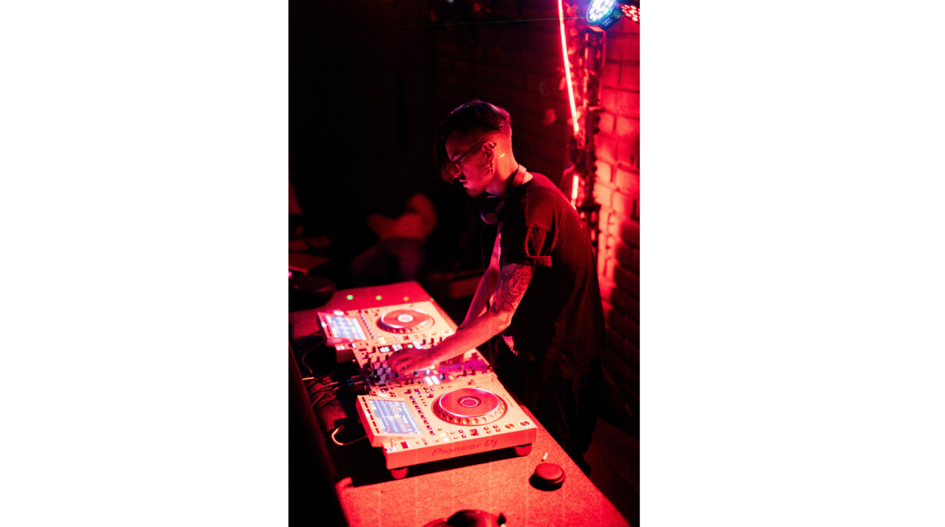 DJ performing behind decks in a club setting