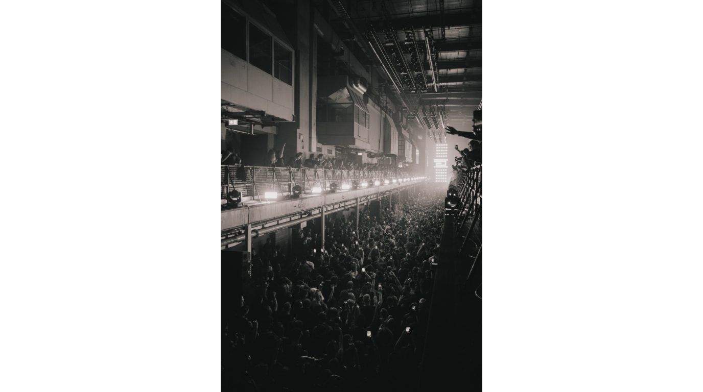 Underground warehouse party with DJ and dancing crowd